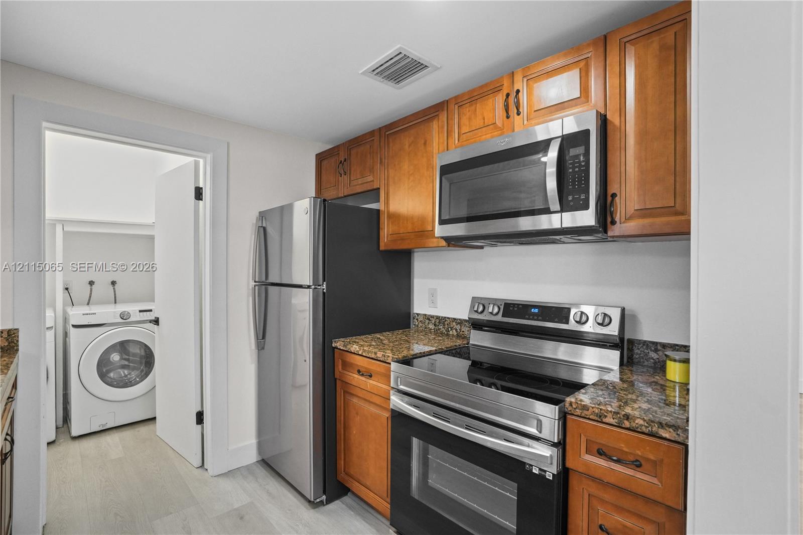 Kitchen featuring wood cabinetry, stone-finish countertops, and a stainless steel appliance suite including a built-in microwave and range Kitchen featuring wood cabinetry, stone-finish countertops, and a stainless steel appliance suite including a built-in microwave and range