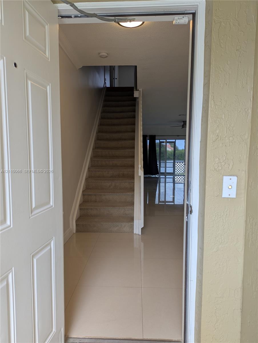Entrance featuring large-format ceramic tile flooring, a carpeted staircase with a white railing, and flush-mount ceiling lighting