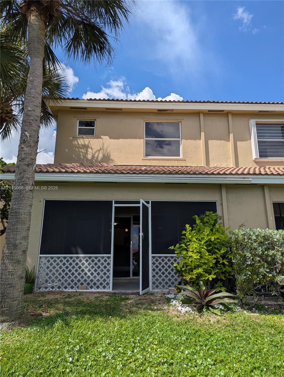 Stucco exterior featuring a screened-in patio, decorative lattice skirting, and a tile roof