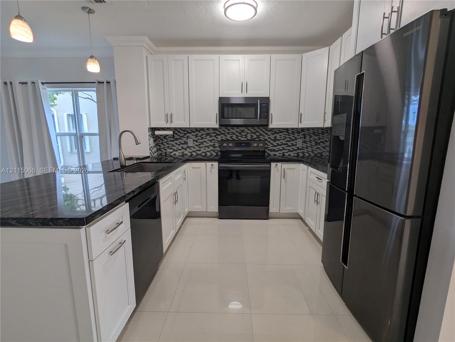 Kitchen featuring white cabinetry, dark stone countertops, patterned tile backsplash, stainless steel appliances, and large-format tile flooring