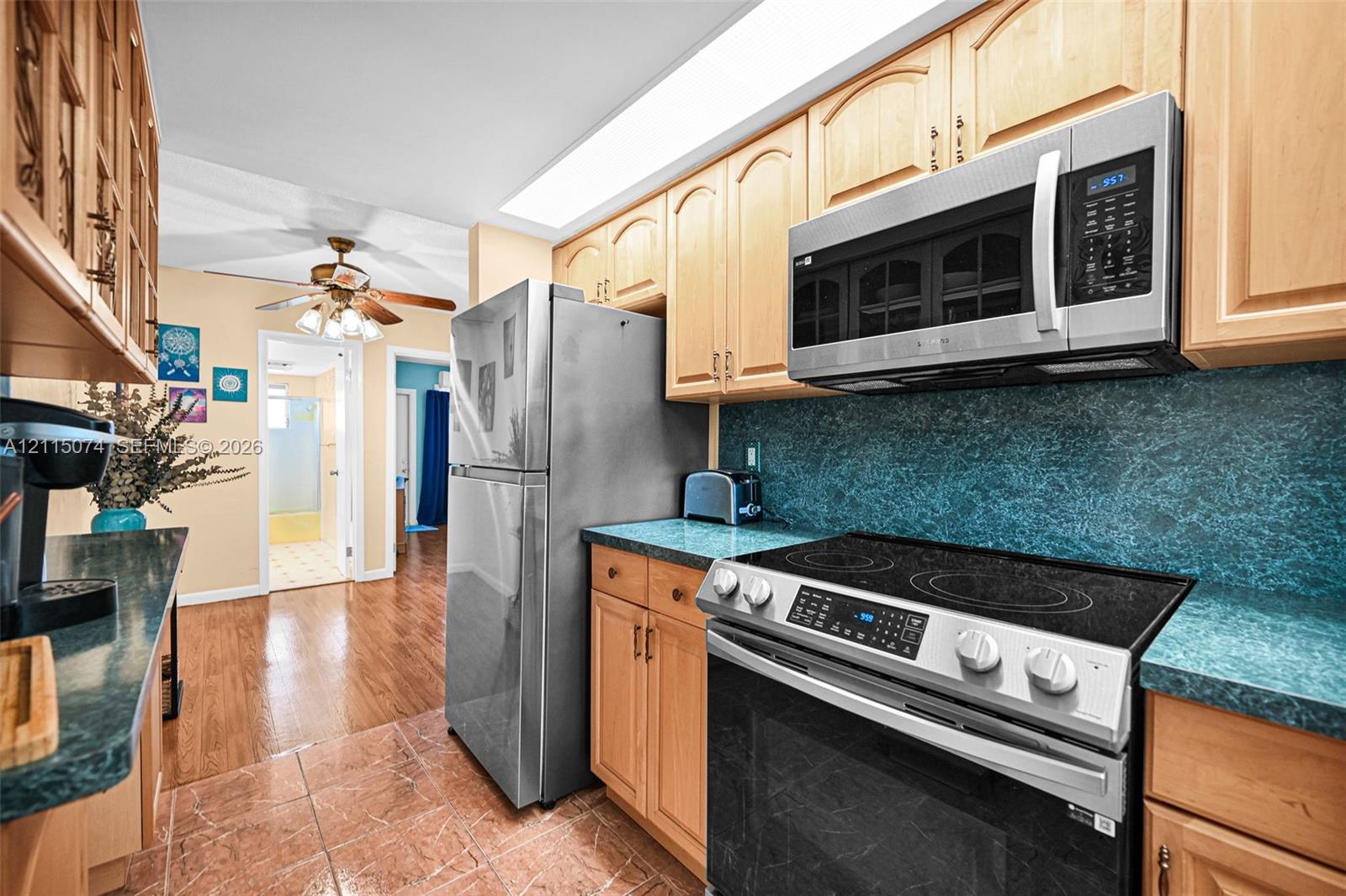Kitchen featuring wood cabinetry, stainless steel appliances, integrated microwave, solid-surface countertops, and tile flooring