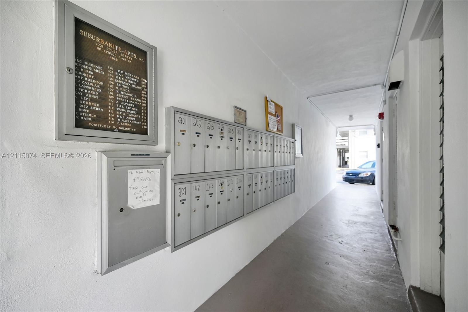 Covered corridor featuring metal mailboxes and a wall-mounted building directory