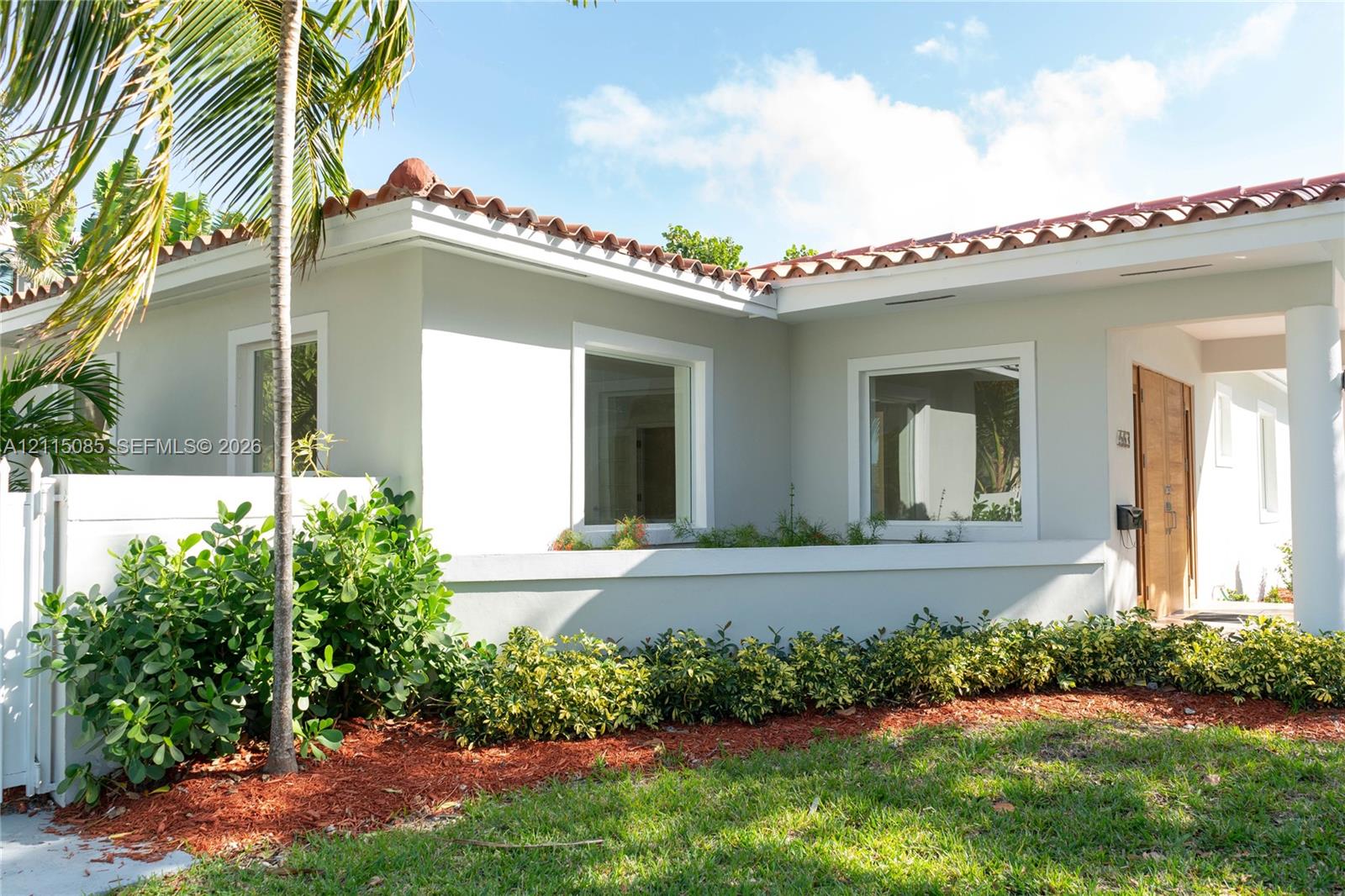 Stucco exterior featuring a clay tile roof, covered entryway, and wood-finish front door