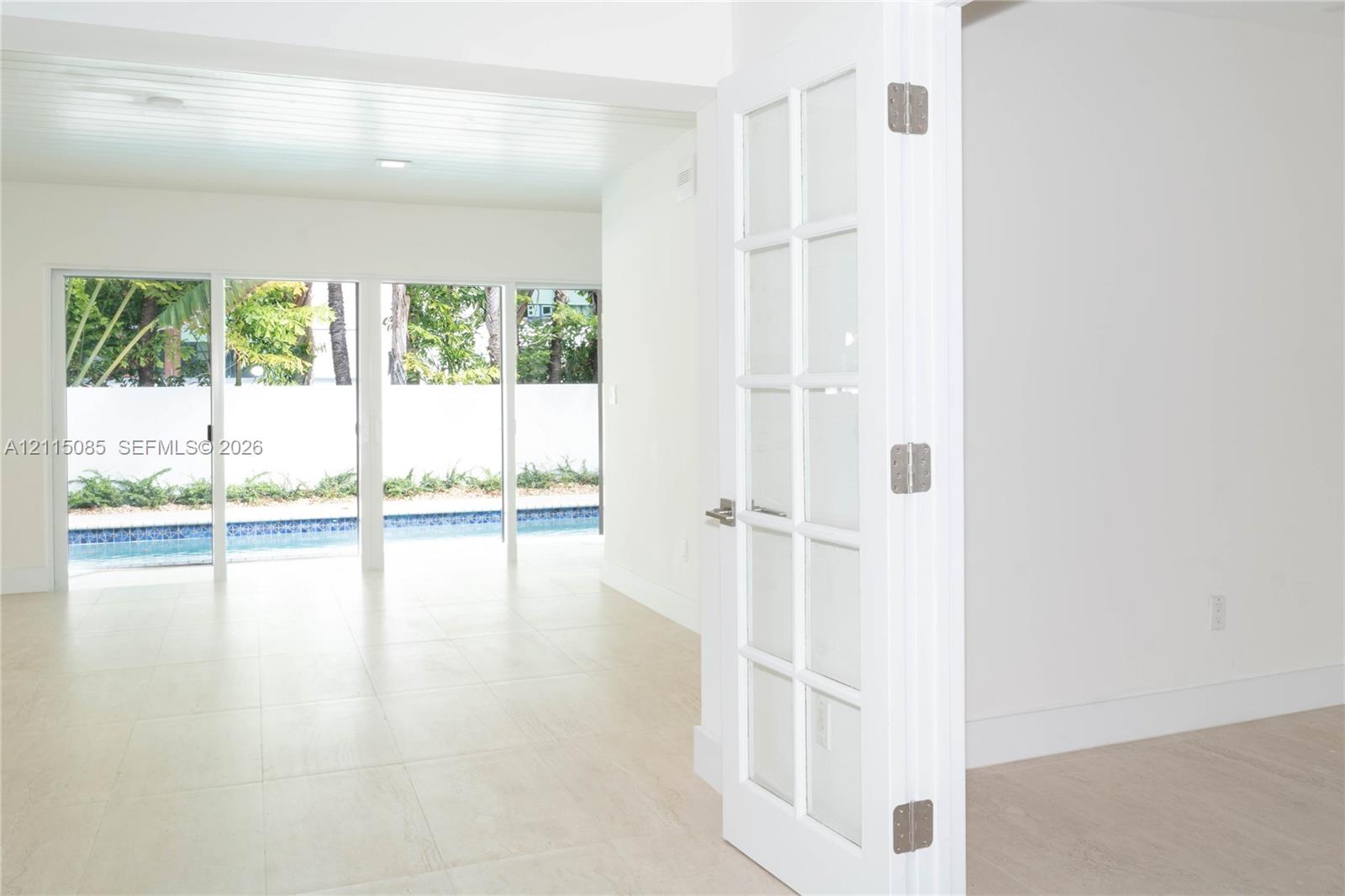 Interior space featuring light-toned porcelain tile flooring, multi-panel glass sliding doors, and a French door with glass inserts