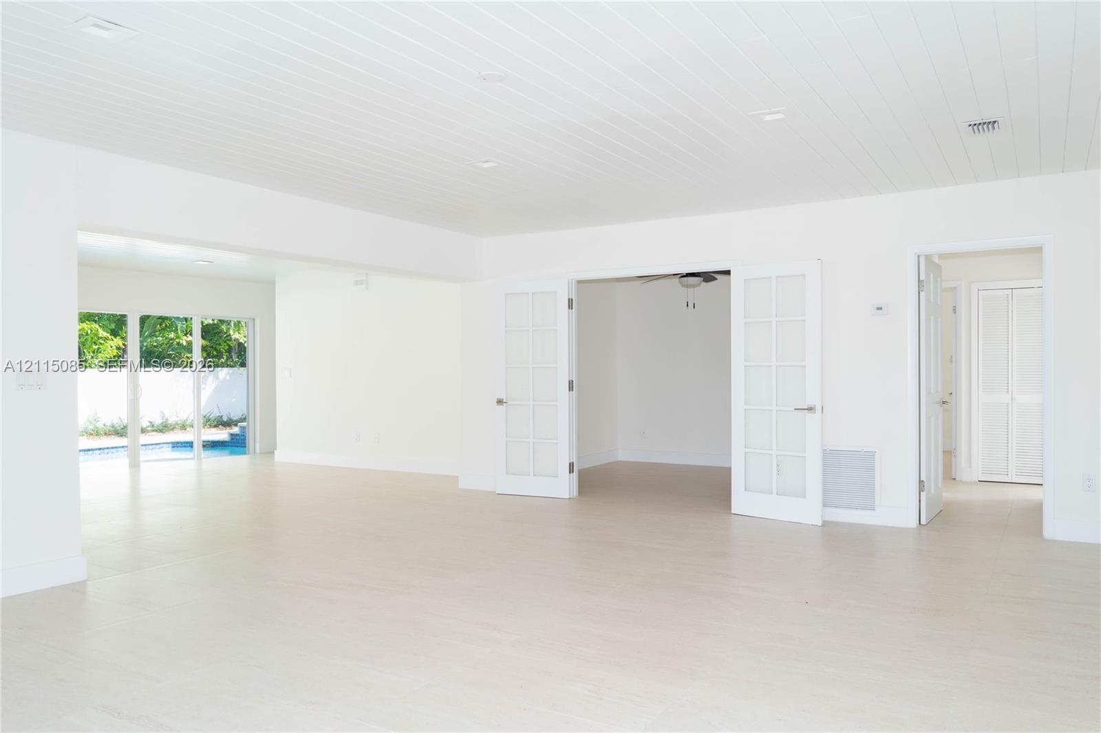 light-toned porcelain tile flooring, tongue-and-groove paneled ceiling, French doors with glass panes, and recessed lighting