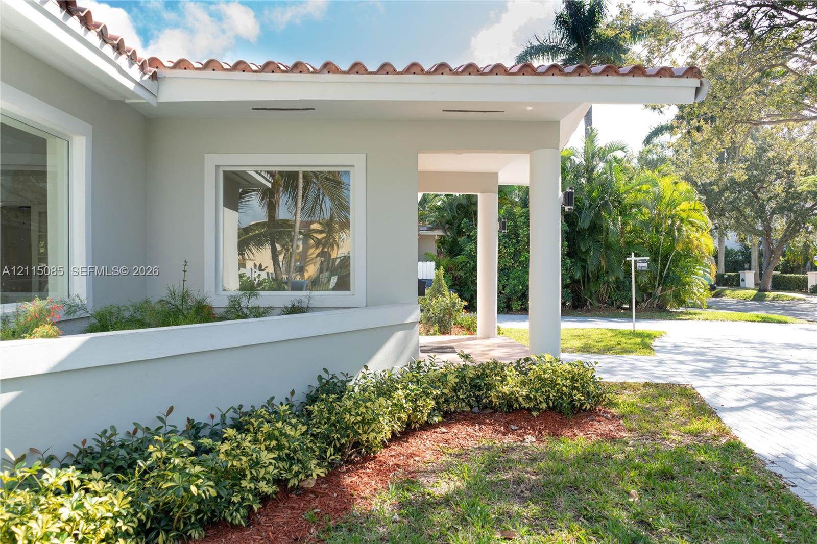 Exterior facade featuring terracotta roof tiles, smooth stucco finish, recessed lighting, and a covered entryway supported by circular columns