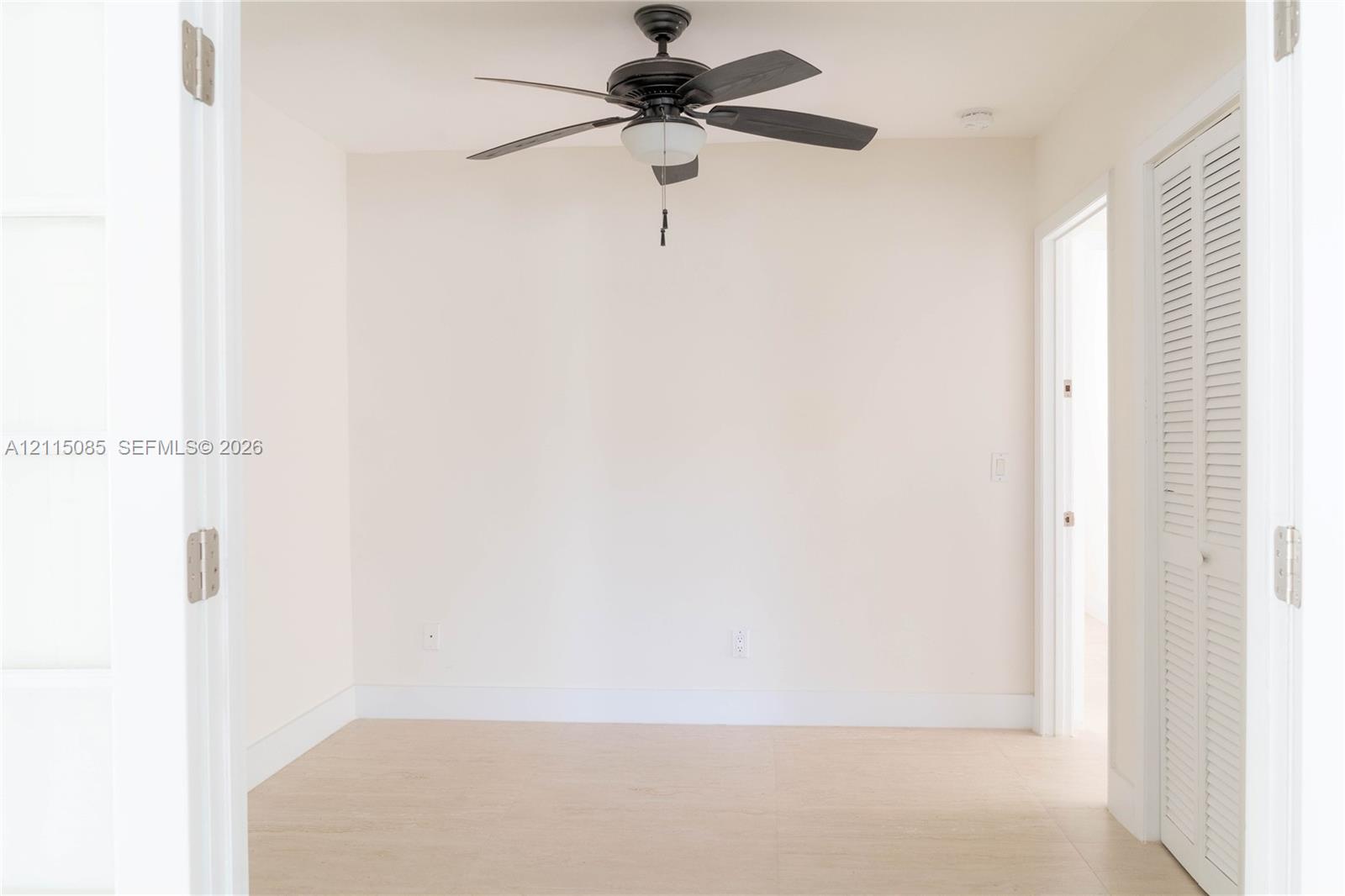 Room featuring French doors, light-toned porcelain tile flooring, a ceiling fan with integrated lighting, and a louvered bi-fold closet door