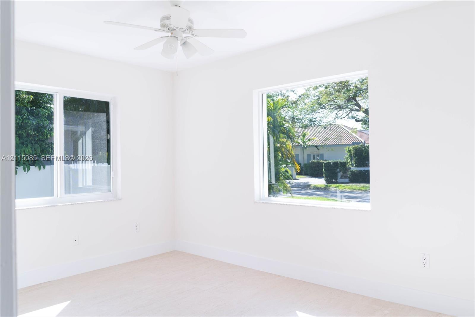 Bright interior room featuring dual windows, neutral wall finishes, and an overhead ceiling fan