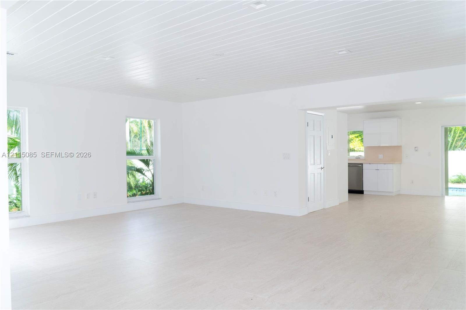 Open-concept interior featuring light-toned porcelain tile flooring, recessed lighting, and a plank-style ceiling