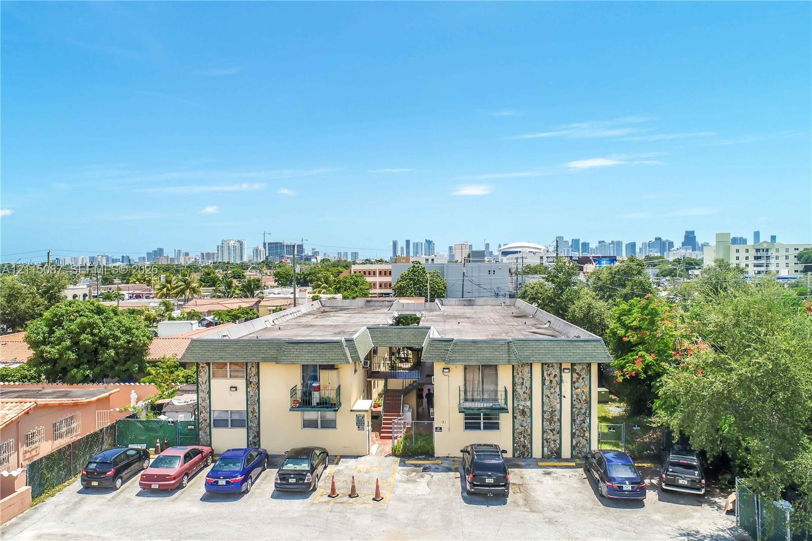 Two-story multifamily property featuring decorative stone exterior accents, individual unit balconies, and dedicated surface parking