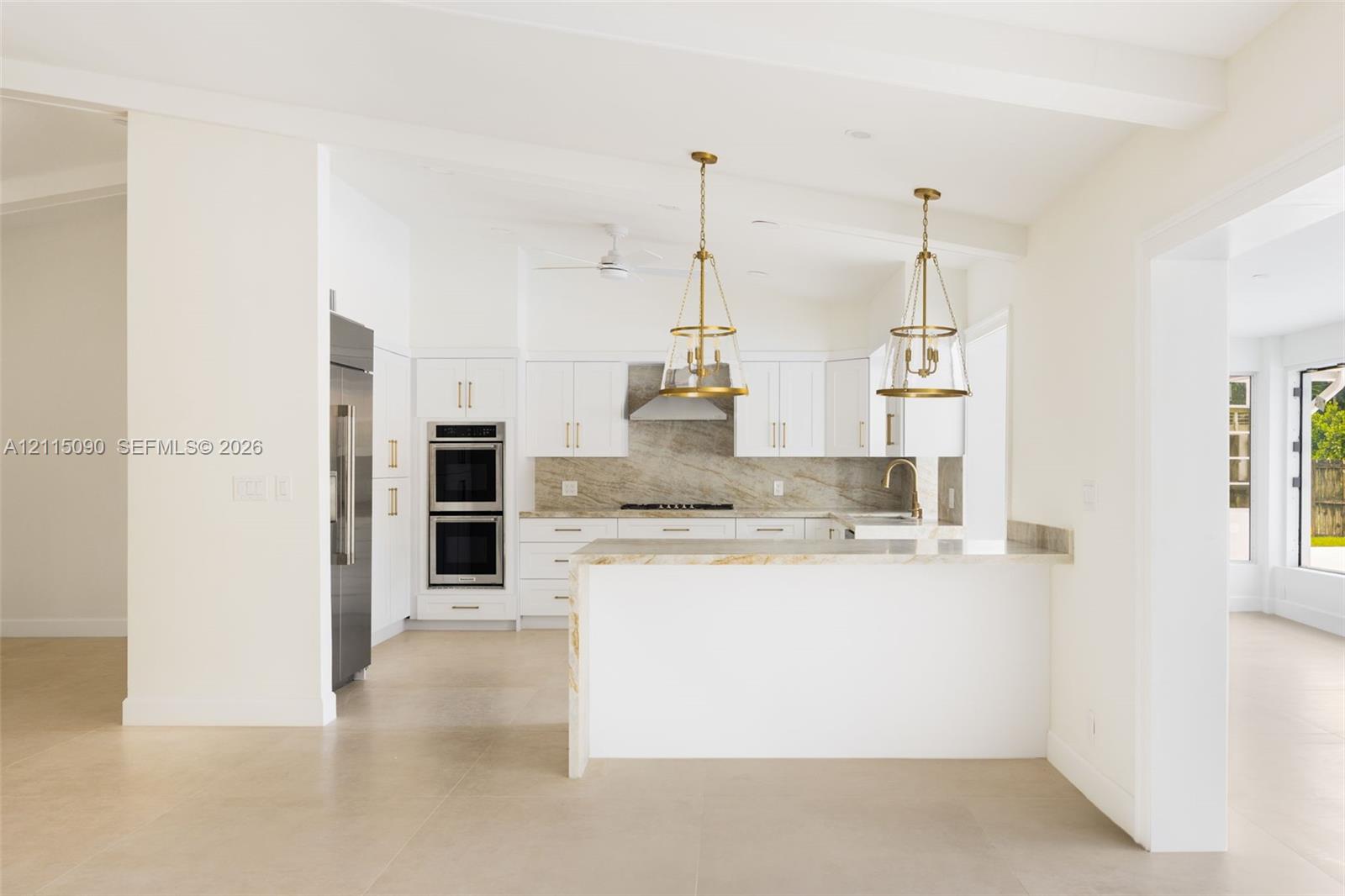 Kitchen featuring white shaker-style cabinetry, stone-surface countertops, dual stainless steel wall ovens, stone-finish backsplash, and pendant lighting