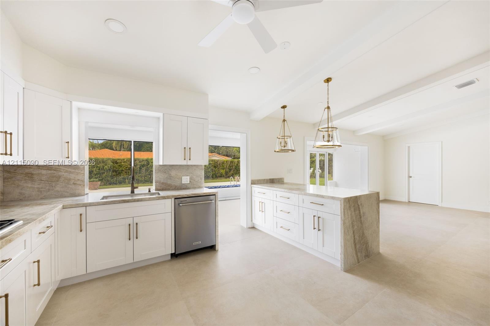 Kitchen featuring white shaker-style cabinetry, waterfall-edge stone countertops, stainless steel dishwasher, pendant lighting, and oversized tile flooring
