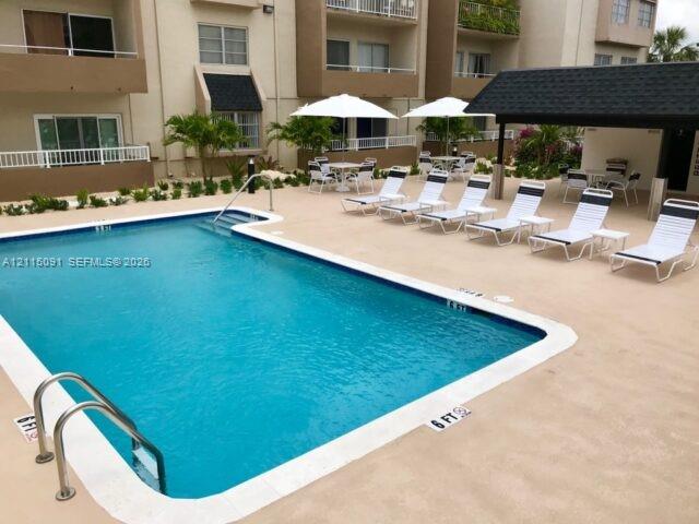 Swimming pool with tiled perimeter, concrete deck, and covered pavilion