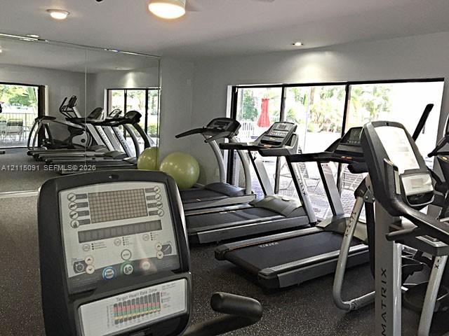 Fitness center featuring wall-to-wall mirrors, recessed lighting, rubberized flooring, and expansive floor-to-ceiling glass doors