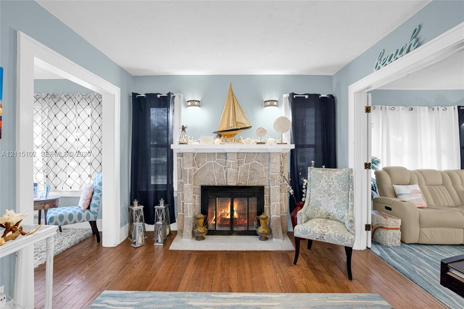 Stone fireplace surround with a wood mantle, wood-finish flooring, and wall-mounted light fixtures