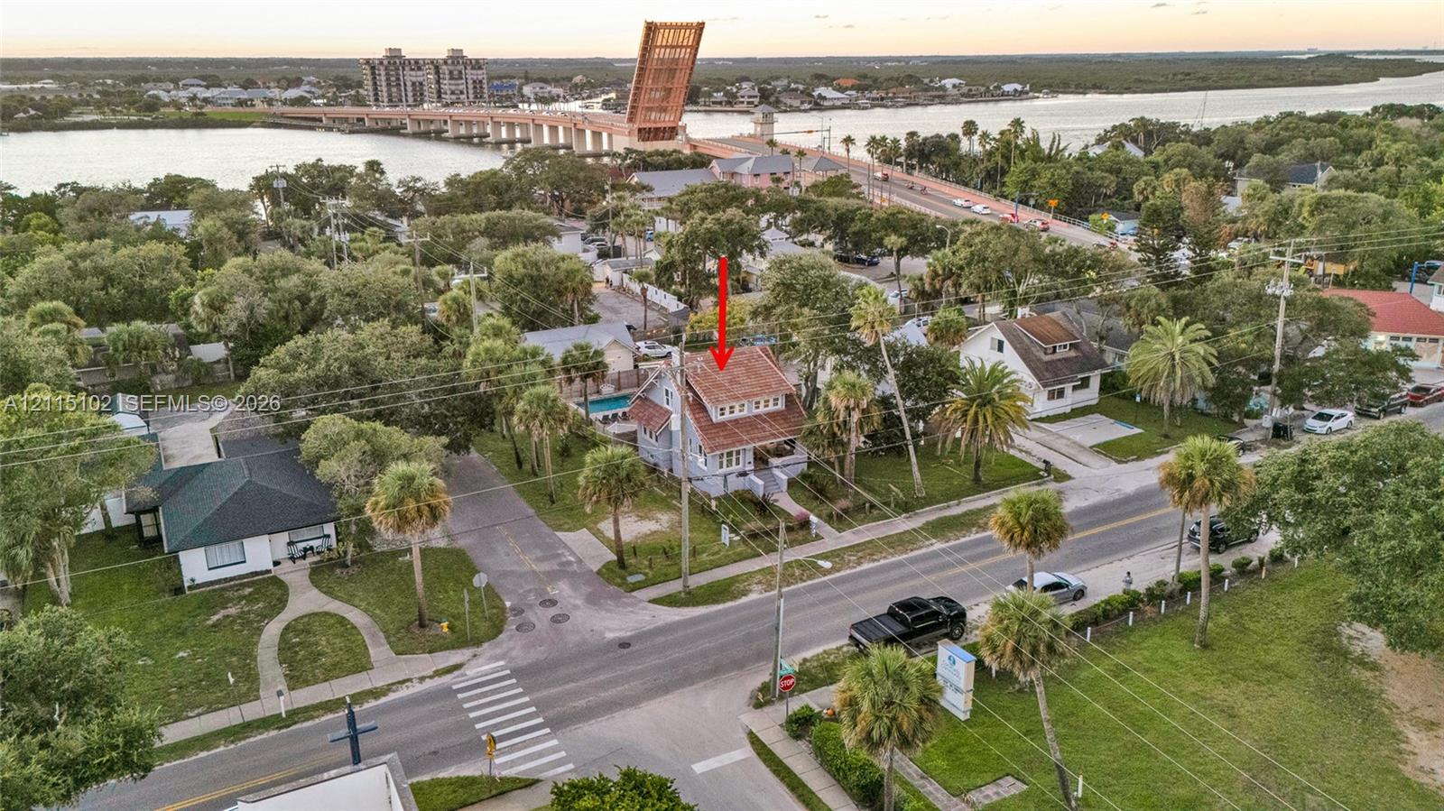 Two-story residence featuring a shingled roof, exterior staircases, and a private rear swimming pool, situated on a corner lot with mature palm trees