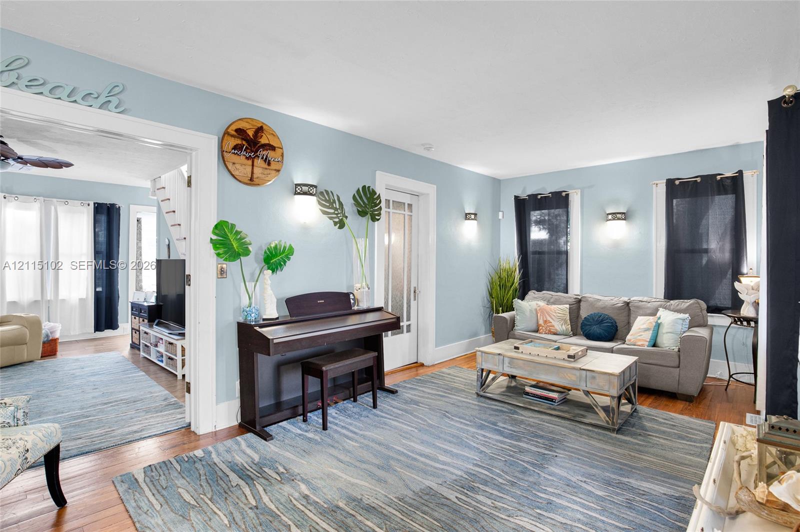 Living space featuring wood-finish flooring, white door and window casings, multiple wall-mounted light fixtures, and a glass-panel door