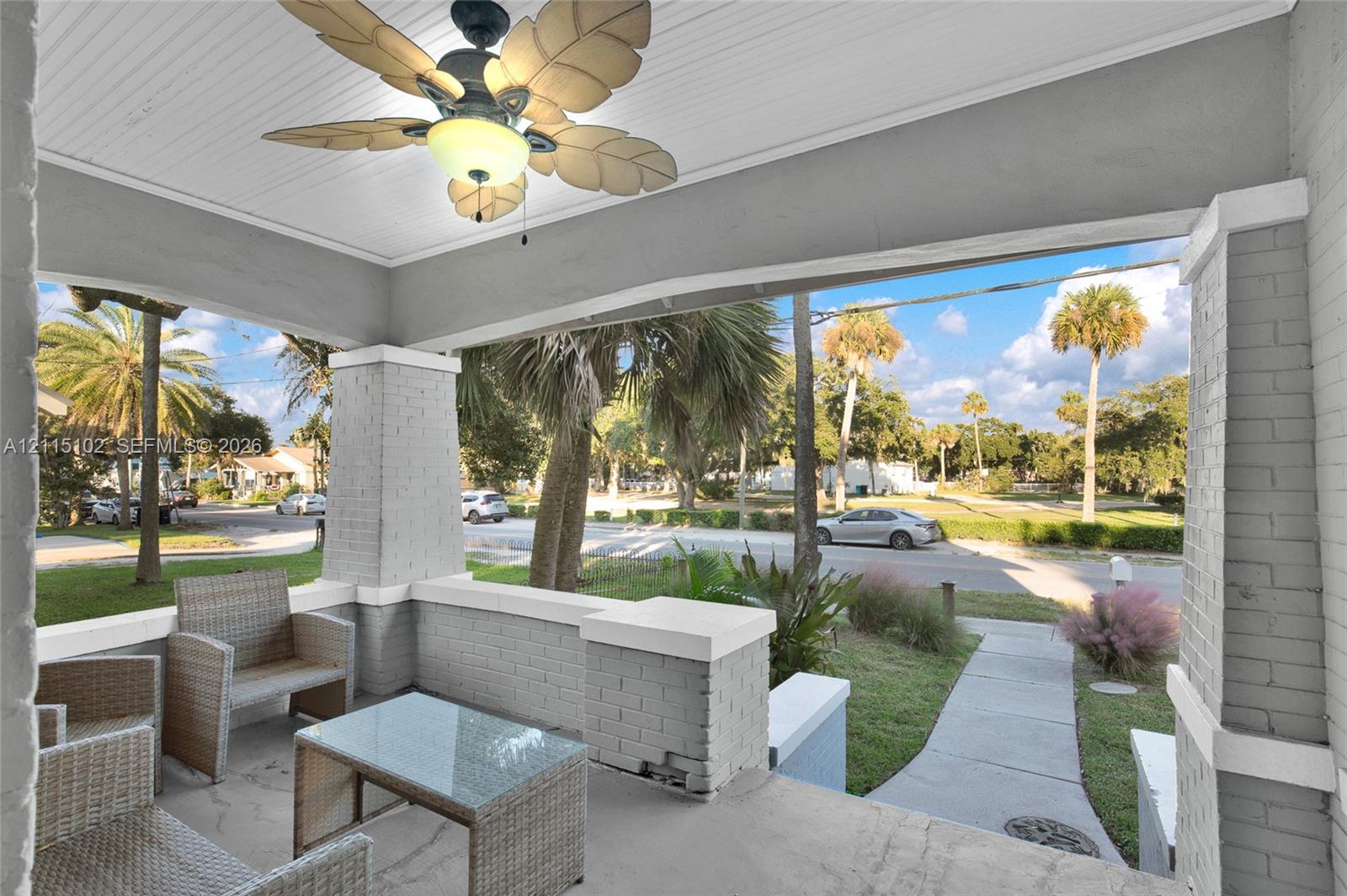Covered front porch featuring a painted brick foundation, concrete flooring, beaded-board ceiling, and a palm-leaf blade ceiling fan
