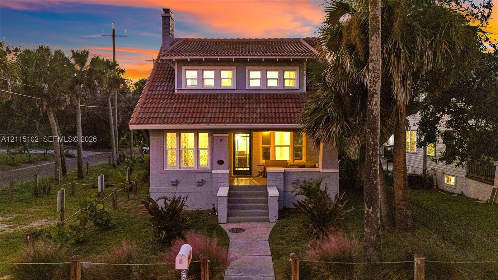 Two-story exterior featuring a clay tile roof, dormer windows, a covered front porch, and mature palm trees Two-story exterior featuring a clay tile roof, dormer windows, a covered front porch, and mature palm trees