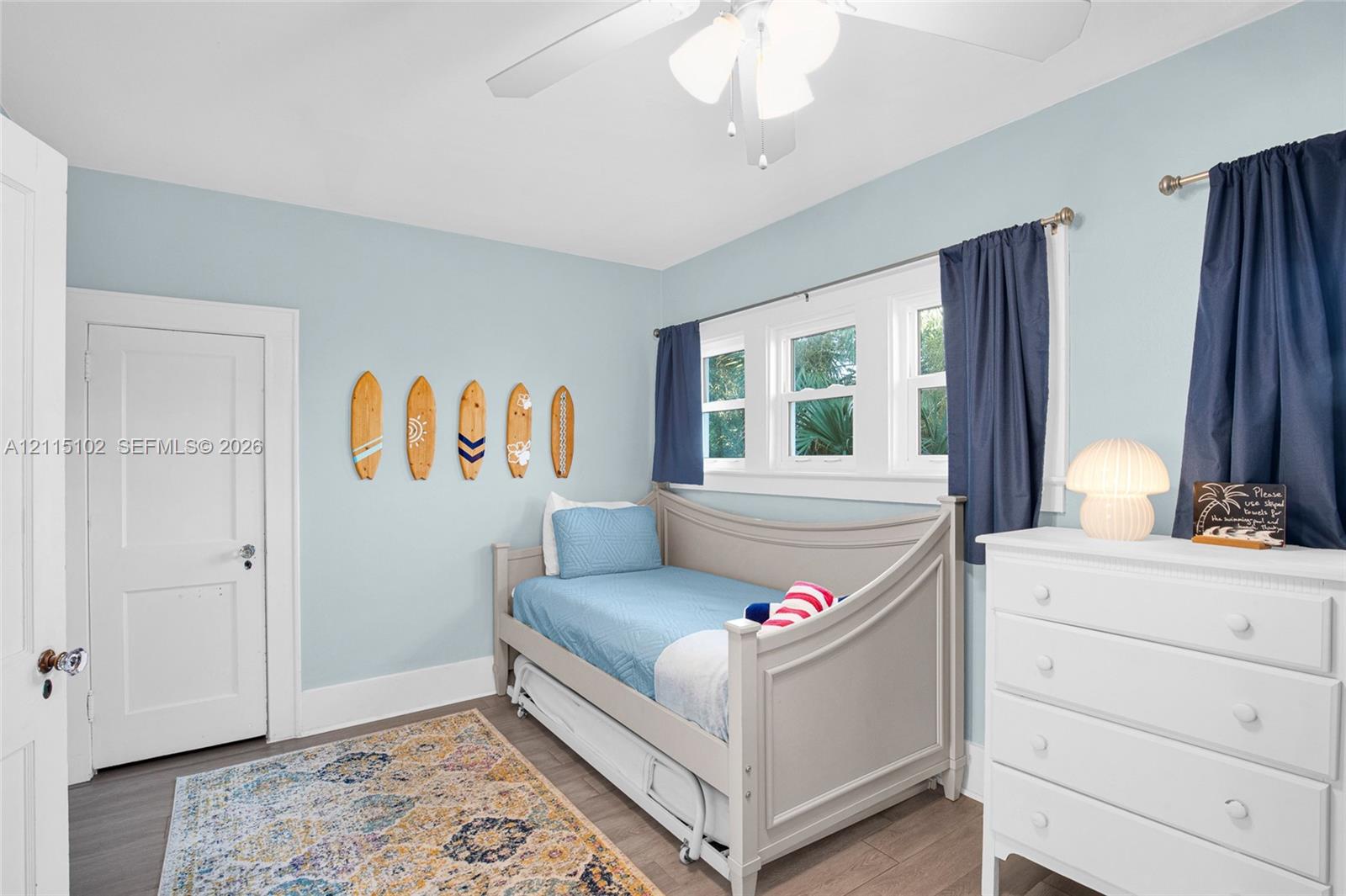 Neutral-toned wall paint, wood-finish flooring, multi-pane window configuration, and three-blade ceiling fan with integrated lighting