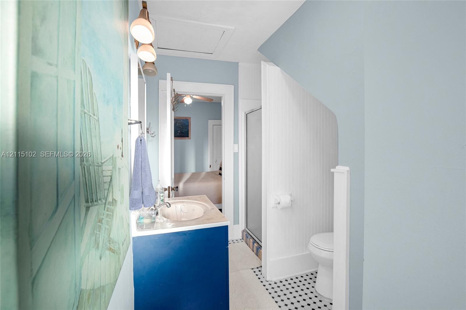 Bathroom featuring a vanity with an integrated sink, beadboard wall paneling, a glass-enclosed shower, and geometric patterned tile flooring
