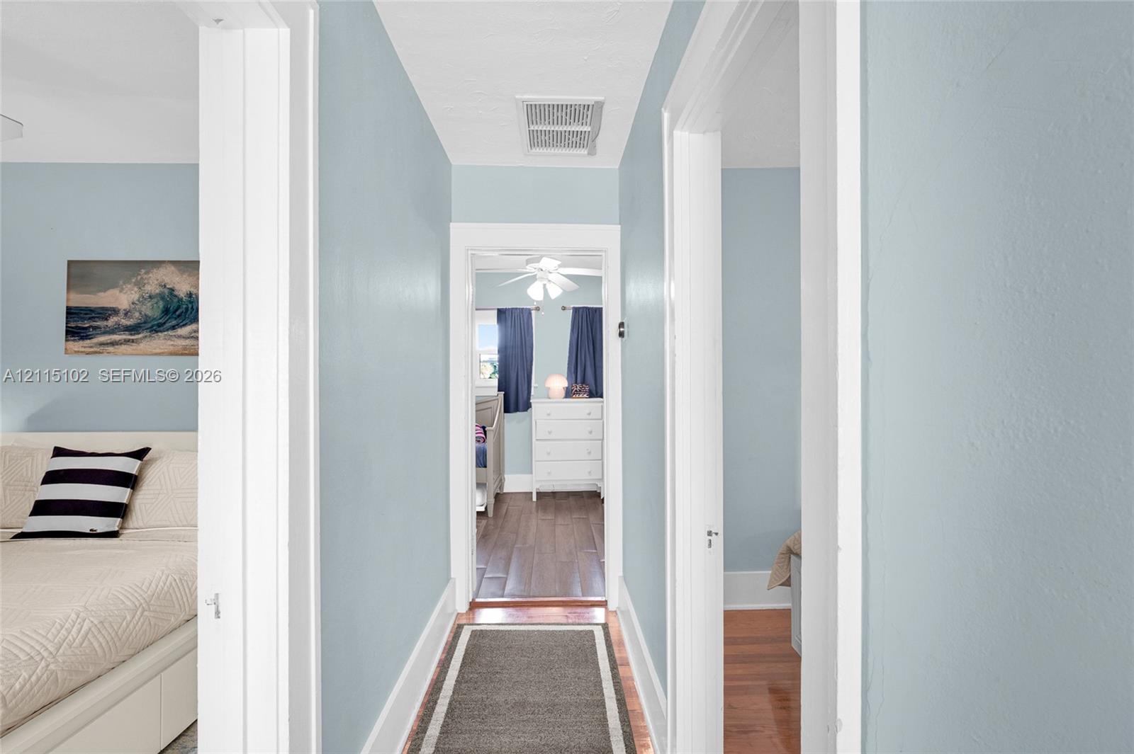 Hallway featuring wood-finish flooring and white door casing