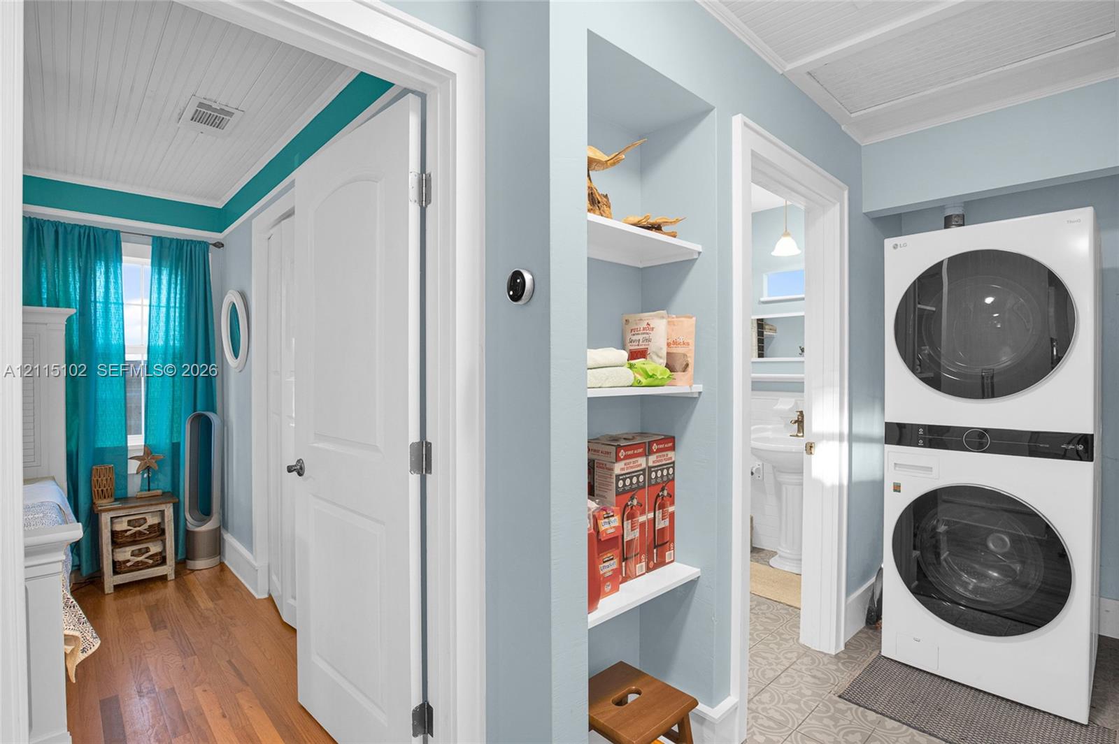 Laundry area featuring stacked washer and dryer, beadboard ceiling, built-in shelving, wood-finish flooring, and tile flooring