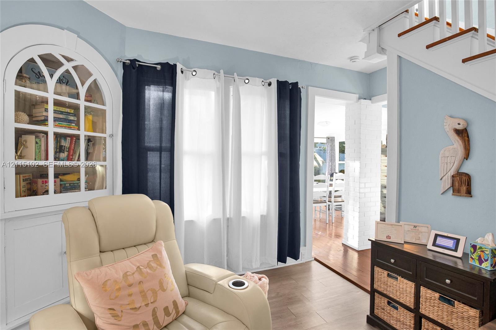 Arched built-in display cabinetry, wood-finish flooring, and a white-painted brick structural column