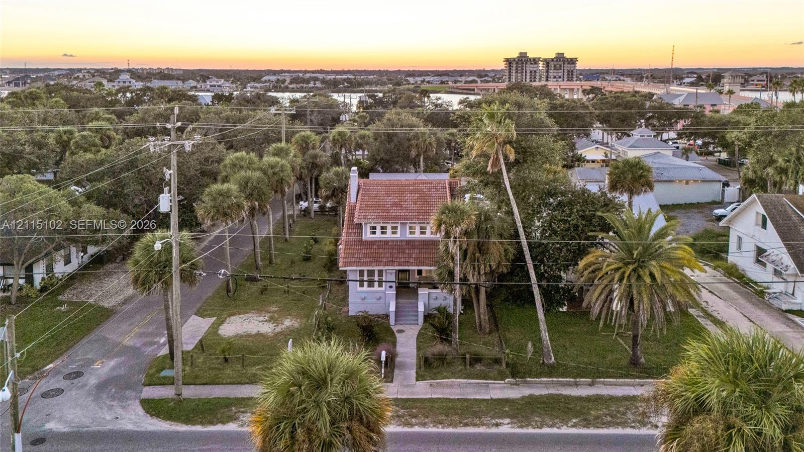 Two-story residence featuring a tile roof, light-toned exterior finish, prominent front-facing gable, and mature palm landscaping