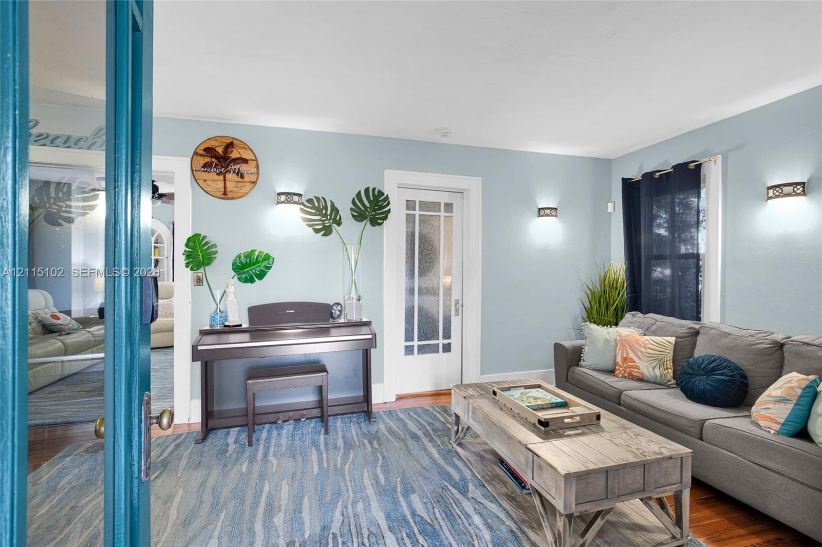 Interior space featuring hardwood flooring, glass-paned French doors, and wall-mounted sconce lighting