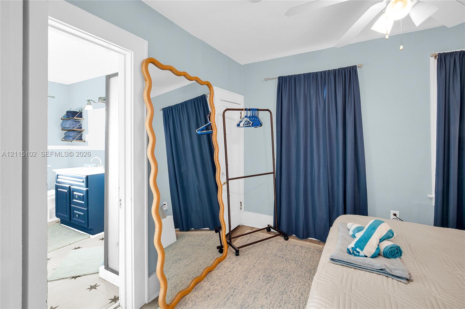 Bedroom featuring a ceiling-mounted light fixture with fan and wall-to-wall drapery hardware