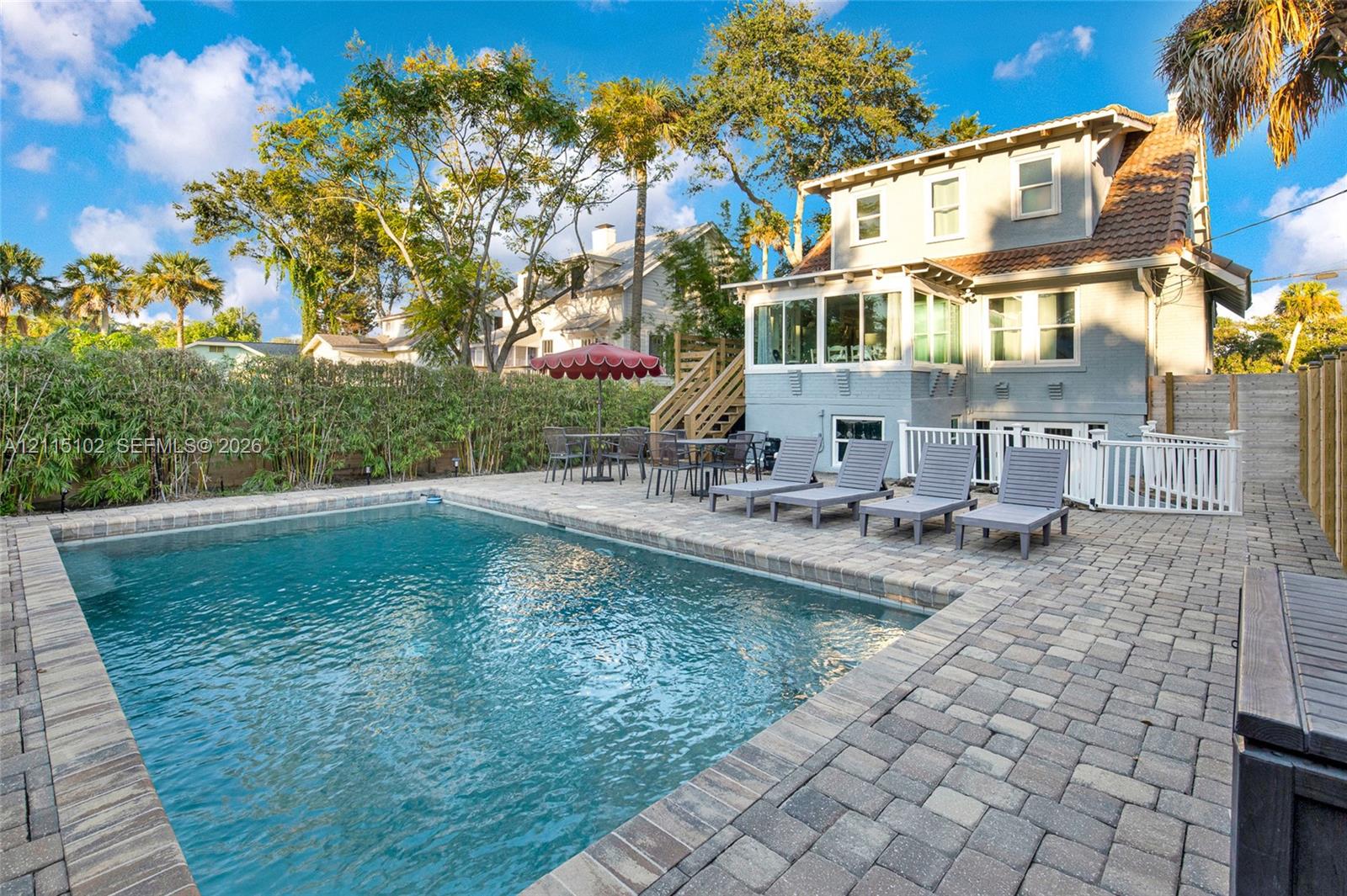 In-ground swimming pool with stone-paver decking and white picket perimeter fencing
