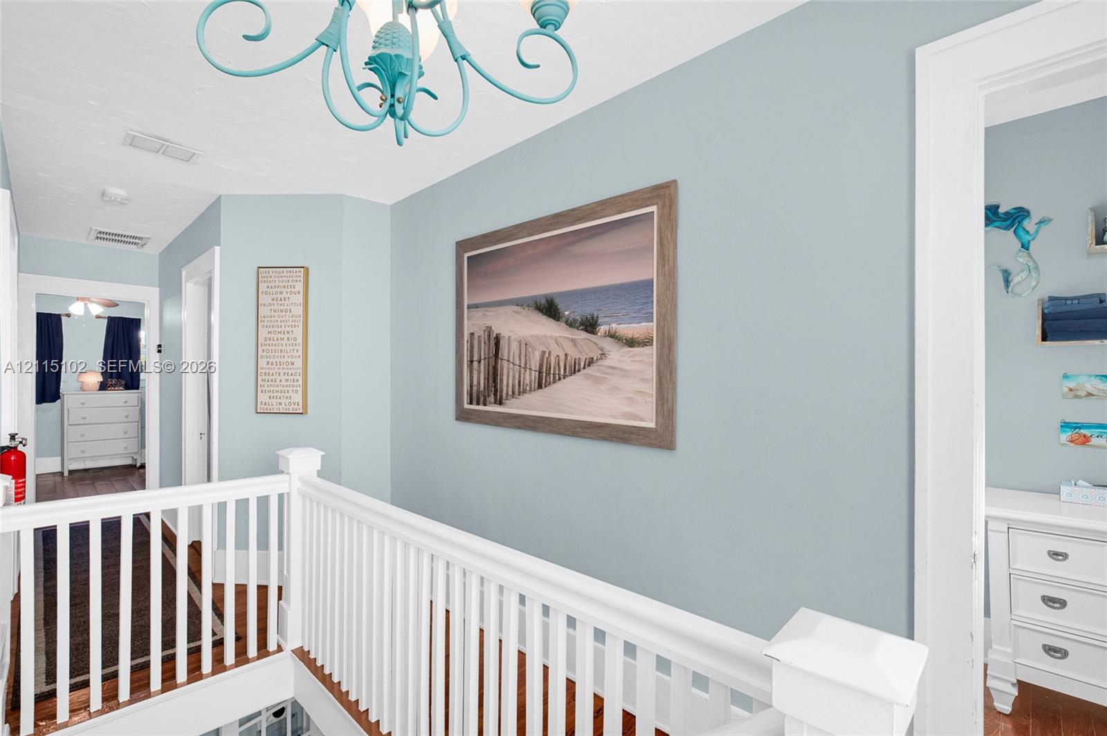 Light blue painted walls, white wooden balustrade, wood-finish flooring, and decorative light fixture
