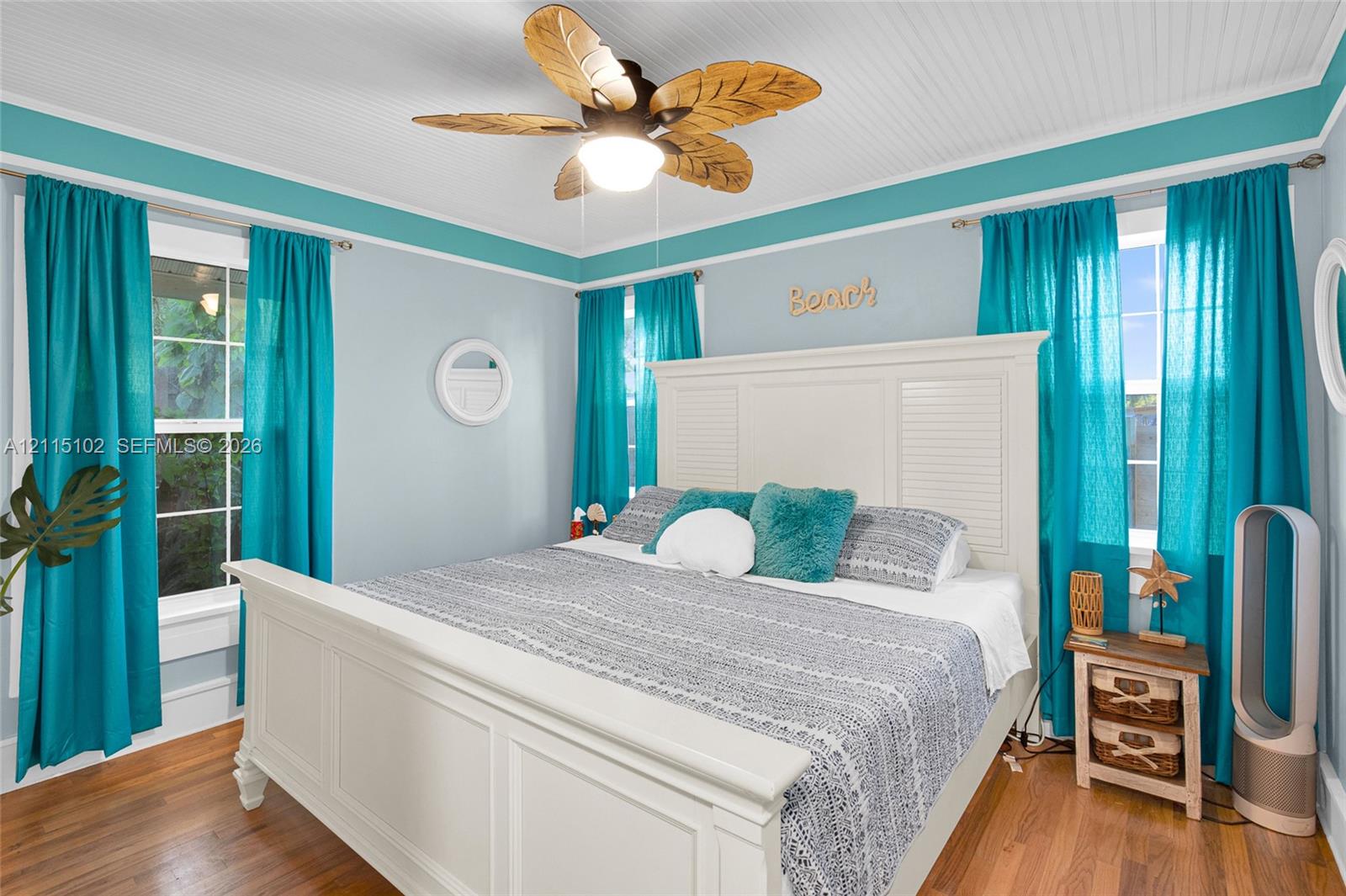 Beadboard ceiling featuring a paddle-style ceiling fan with integrated lighting, wood-finish flooring, and multi-pane windows