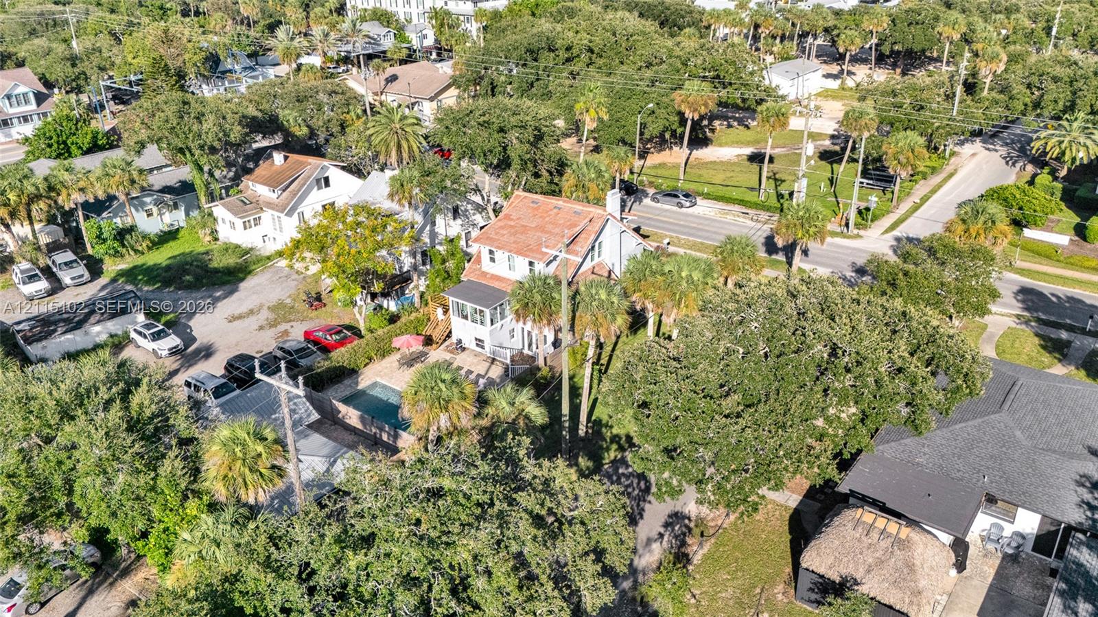 Aerial perspective featuring an in-ground swimming pool, masonry hardscaping, mature palm trees, and multi-level residential architecture