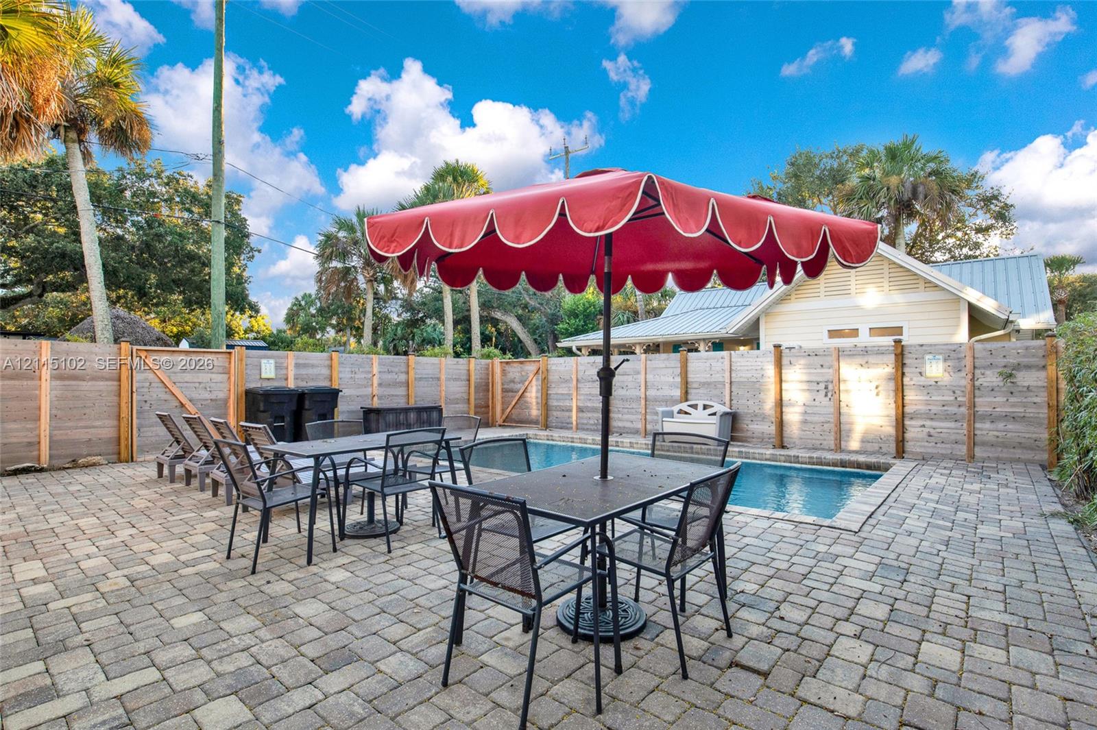 In-ground swimming pool surrounded by a paver patio and horizontal wood privacy fencing