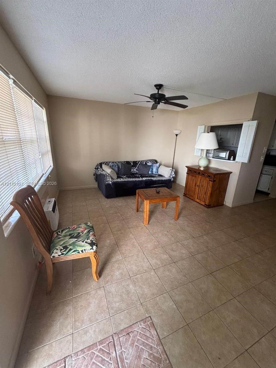 Neutral tile flooring, ceiling fan with integrated lighting, horizontal window blinds, and a built-in pass-through window with shutter doors Neutral tile flooring, ceiling fan with integrated lighting, horizontal window blinds, and a built-in pass-through window with shutter doors