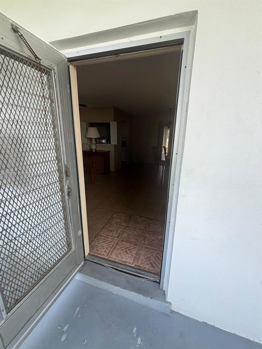 Metal security screen door featuring an integrated diamond-pattern mesh, installed in a white-trimmed doorway with tiled entry flooring
