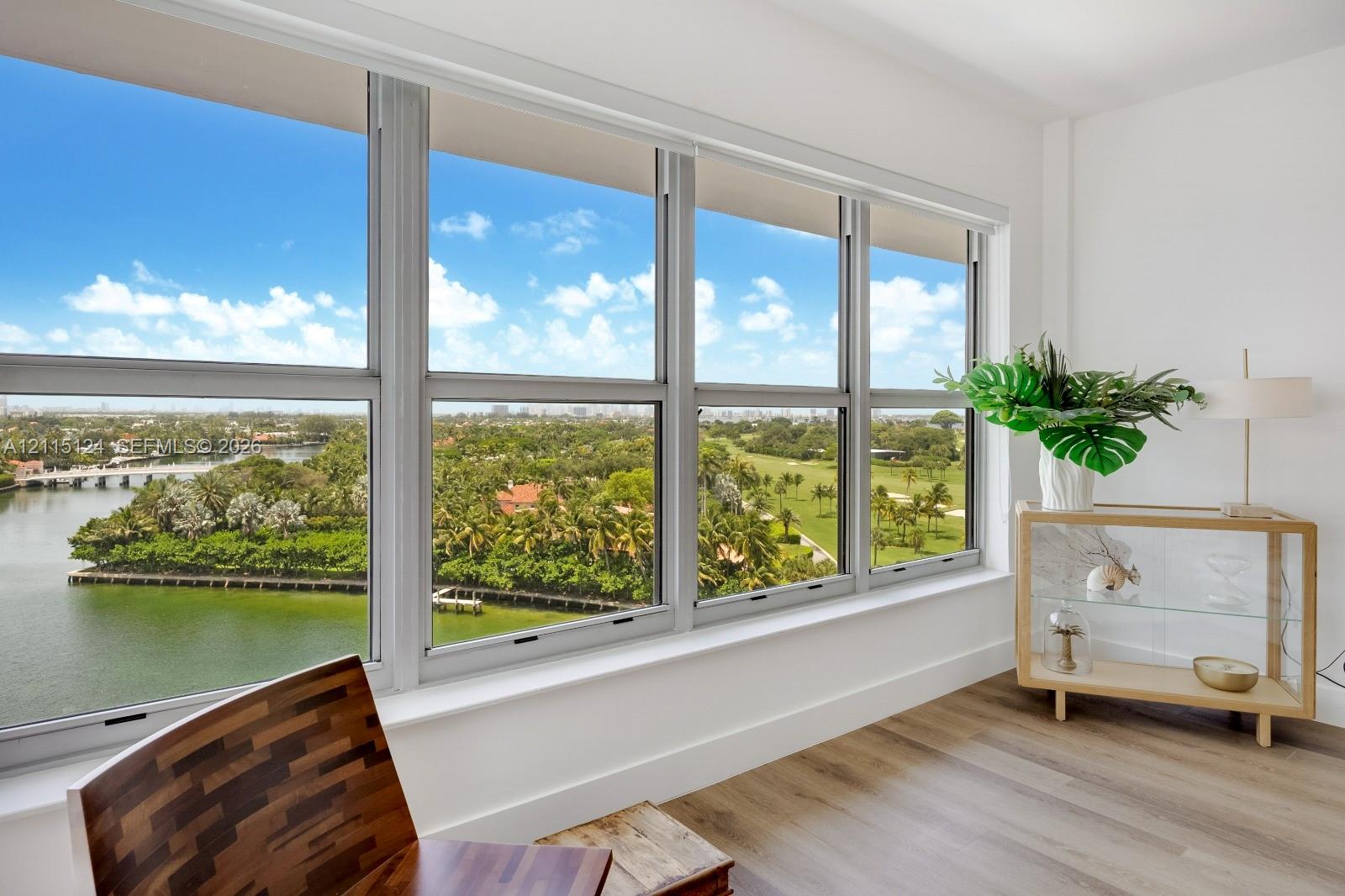 Floor-to-ceiling multi-panel windows, water and green space landscape backdrop, and wood-finish flooring Floor-to-ceiling multi-panel windows, water and green space landscape backdrop, and wood-finish flooring