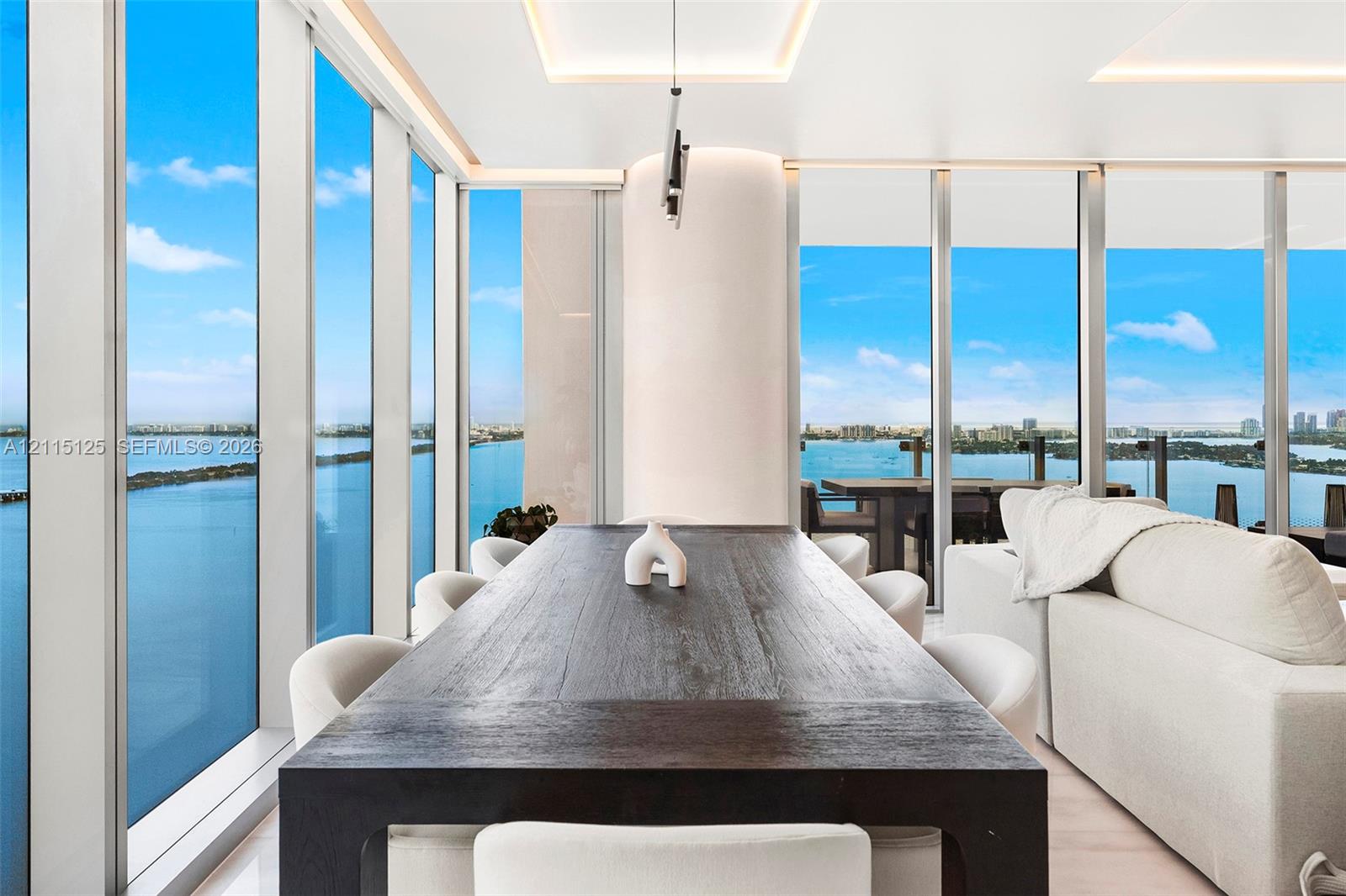 Floor-to-ceiling glass walls, recessed cove lighting, and expansive water scenery