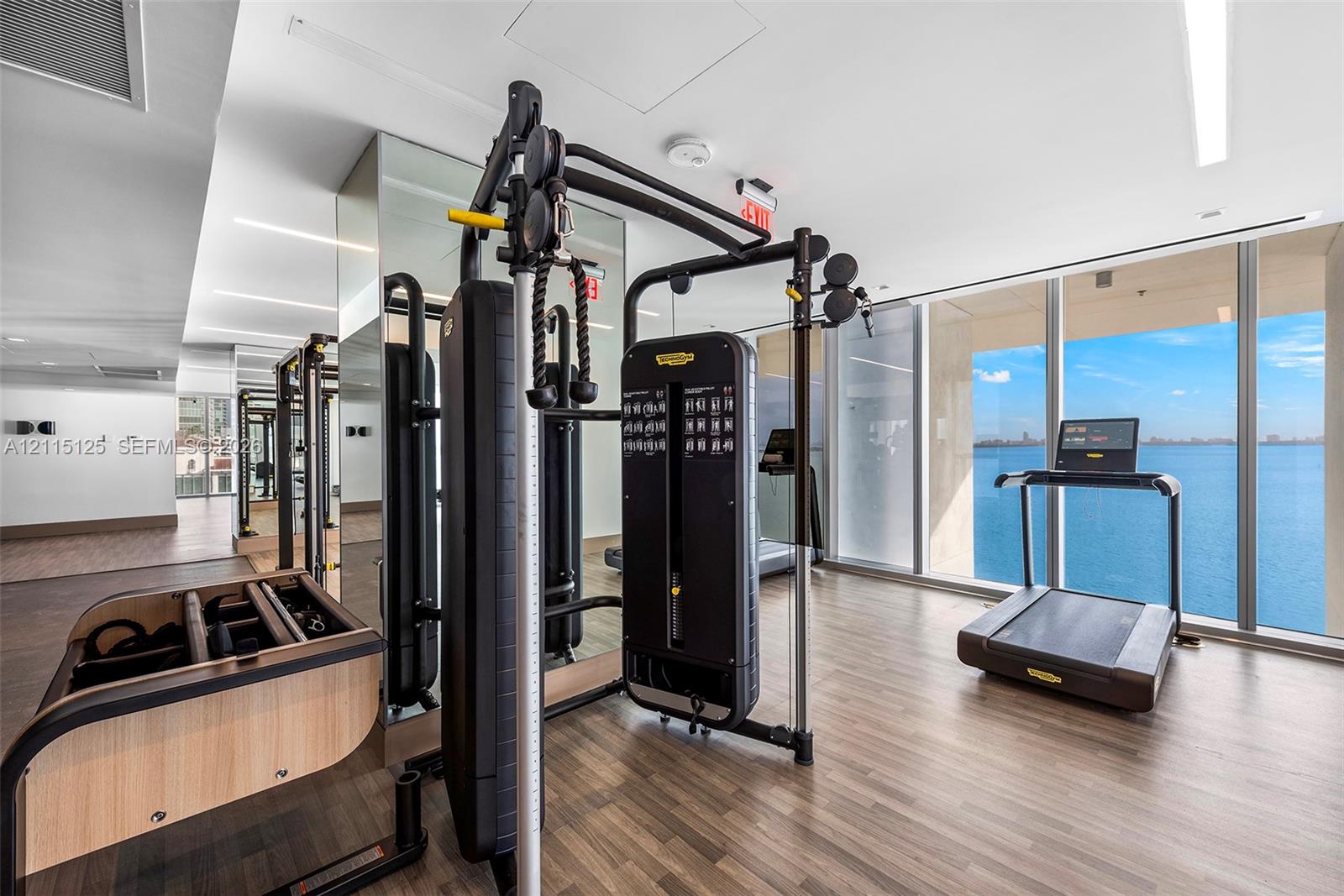 Fitness center featuring floor-to-ceiling windows, water expanse, wood-finish flooring, and recessed linear lighting