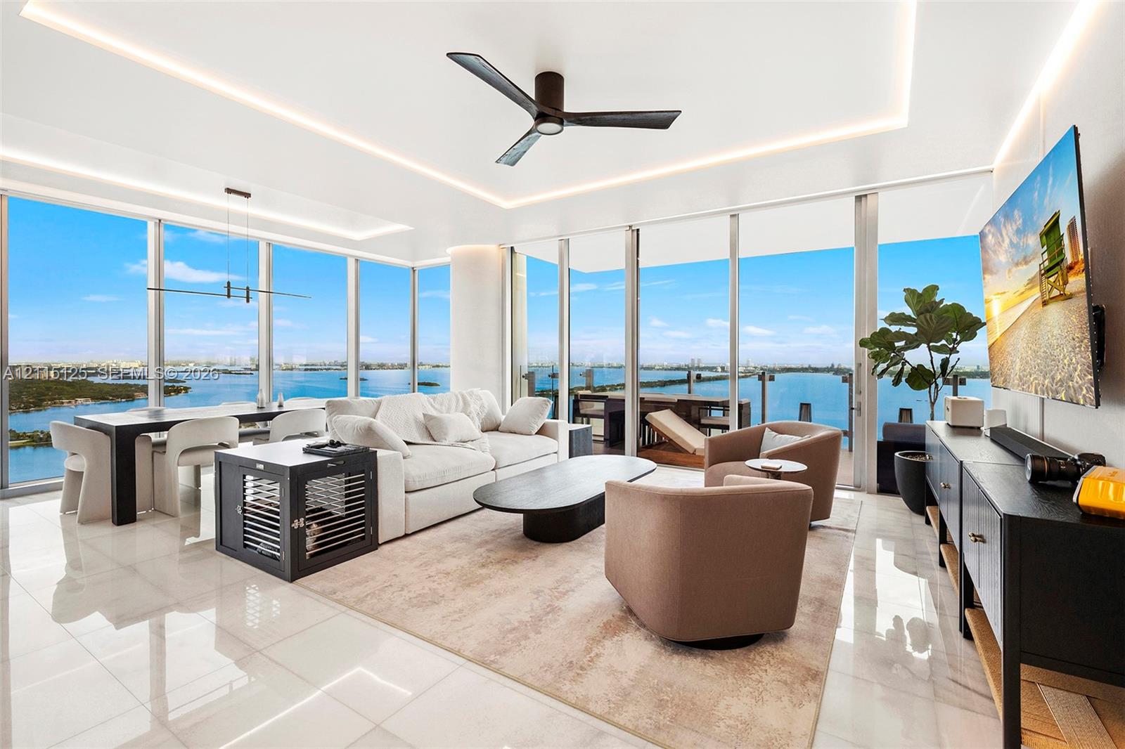 Floor-to-ceiling glass windows, recessed ceiling cove lighting, polished tile flooring, and matte black modern ceiling fan