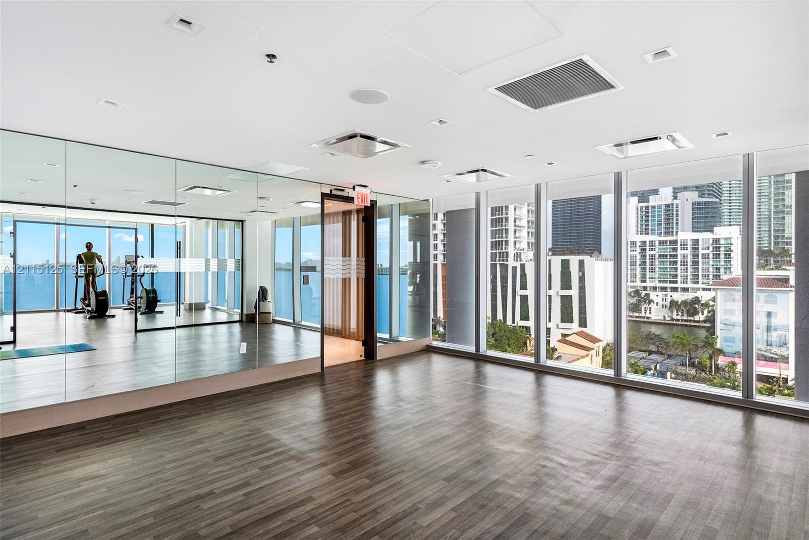 Fitness space featuring floor-to-ceiling windows, wood-finish flooring, full-length wall mirrors, and recessed lighting