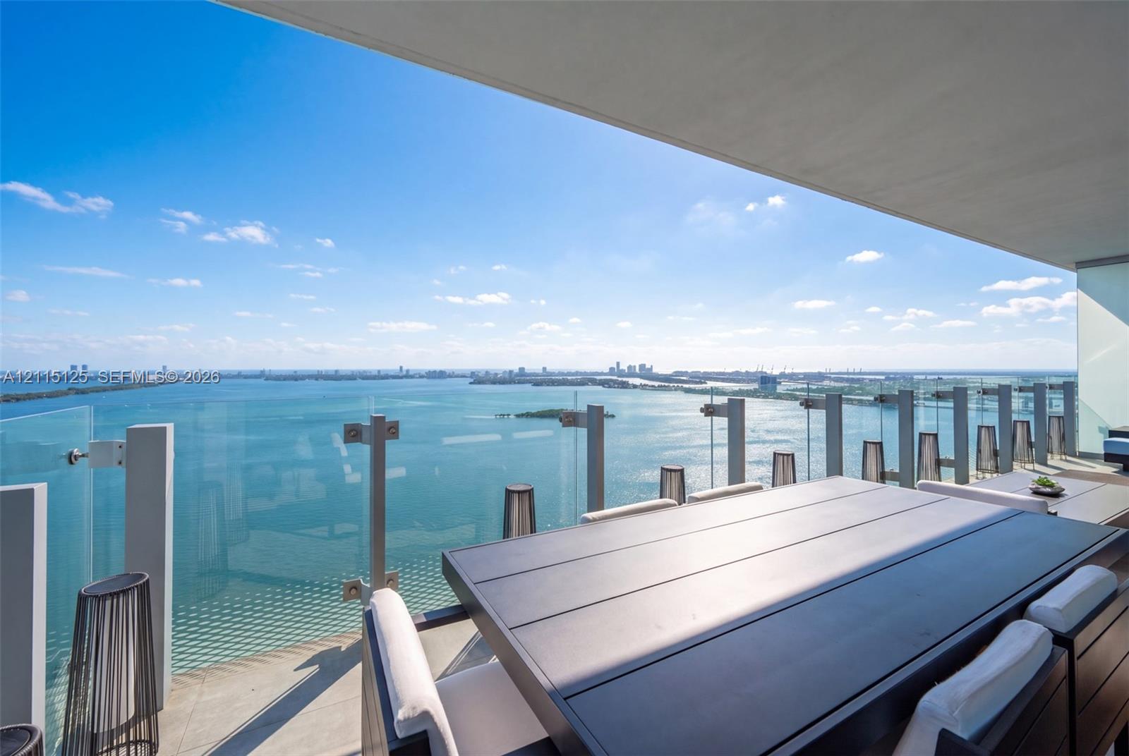 Private balcony featuring large-format tile flooring and frameless glass railing with metallic structural hardware