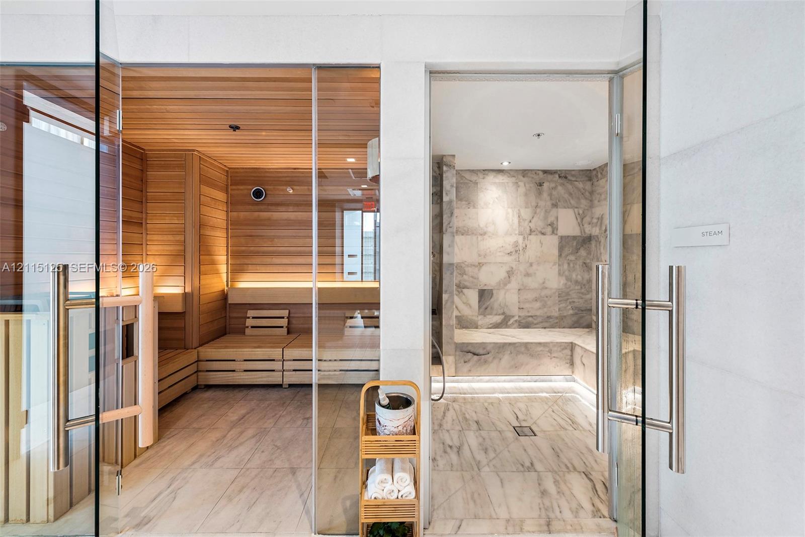 Sauna and steam room featuring glass entry doors, wood-paneled sauna interior with tiered bench seating, and stone-tiled steam room with integrated stone benches
