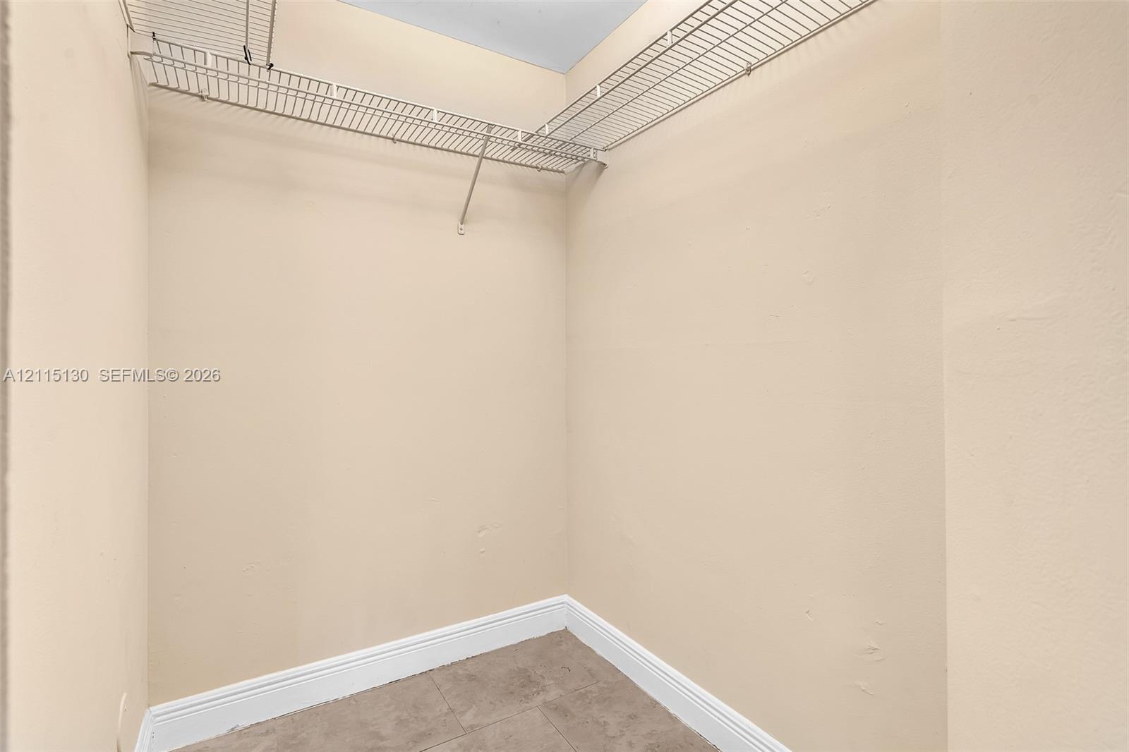 Storage space featuring neutral wall tones, tile flooring, and installed white wire shelving