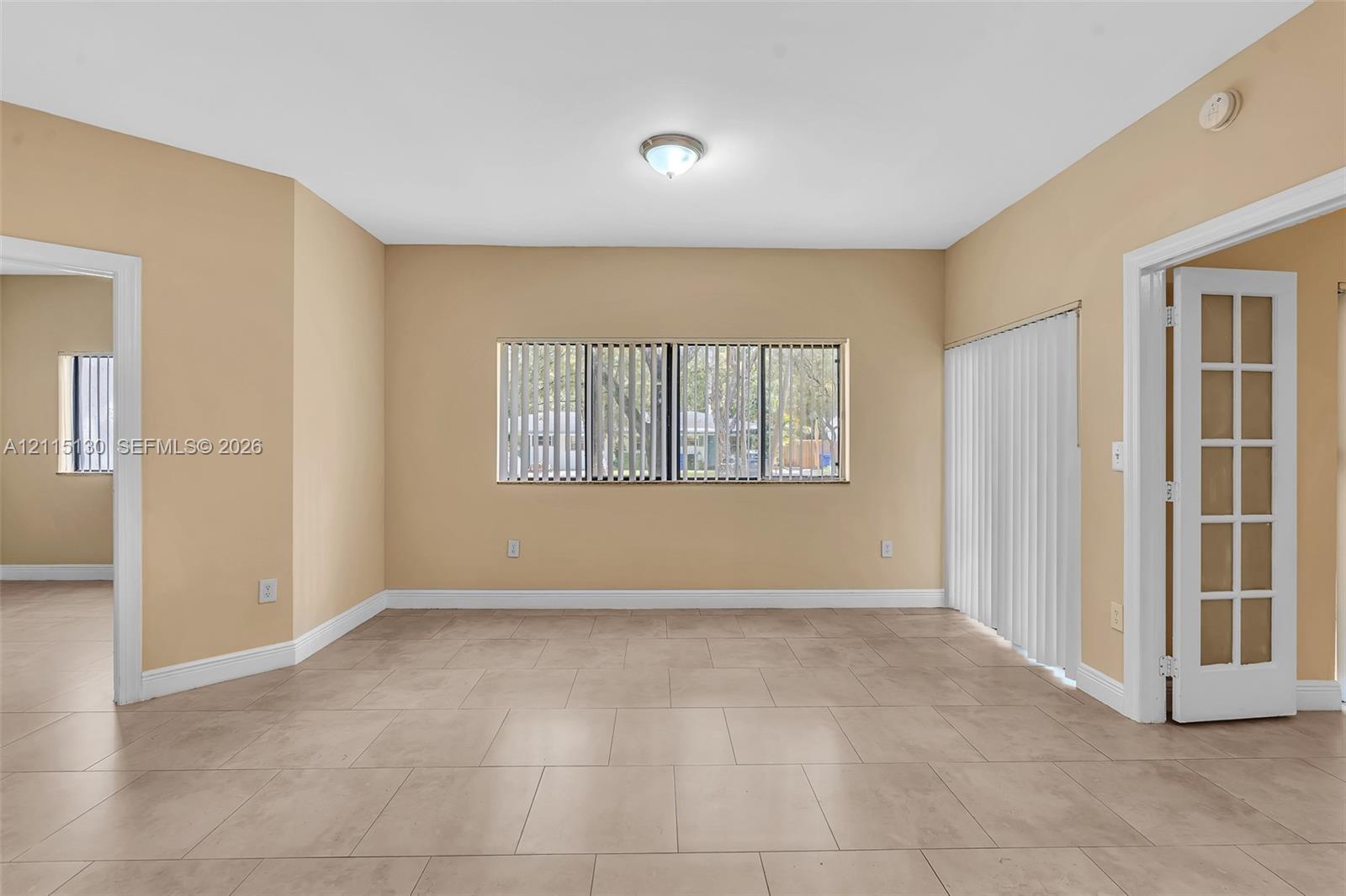 Neutral-toned tile flooring, horizontal blinds, vertical sliding blinds, and a white French door with glass panels