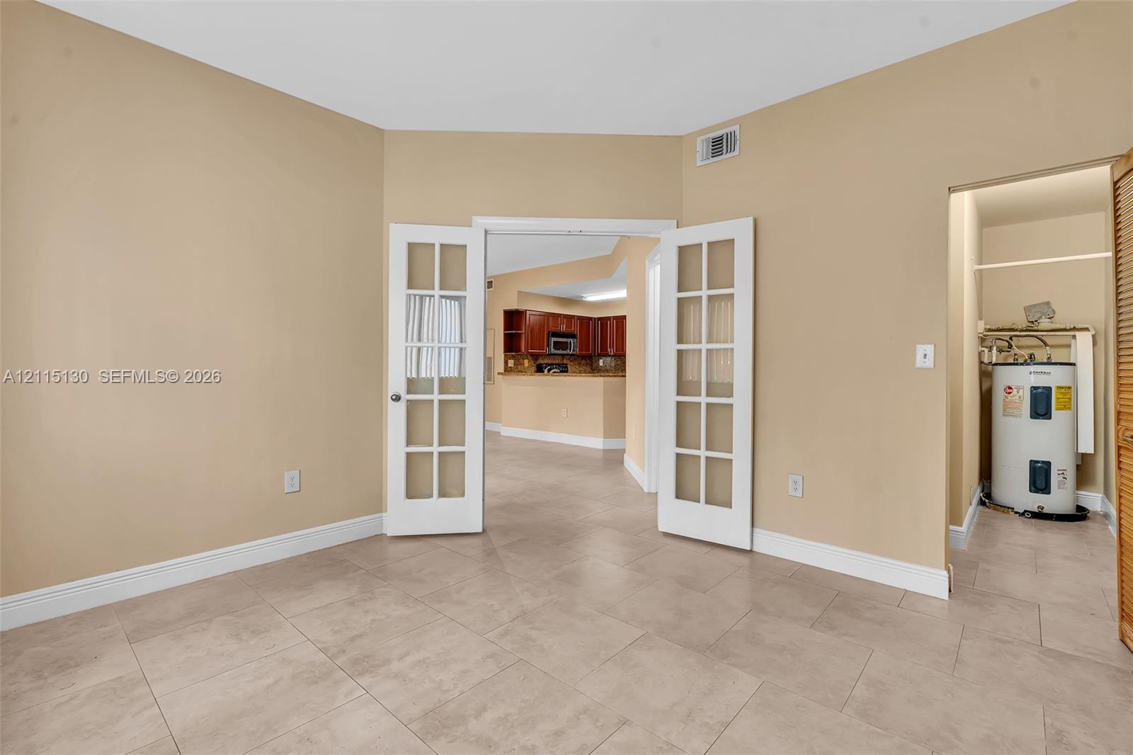 Room featuring large-format ceramic tile flooring and white French doors with glass panes