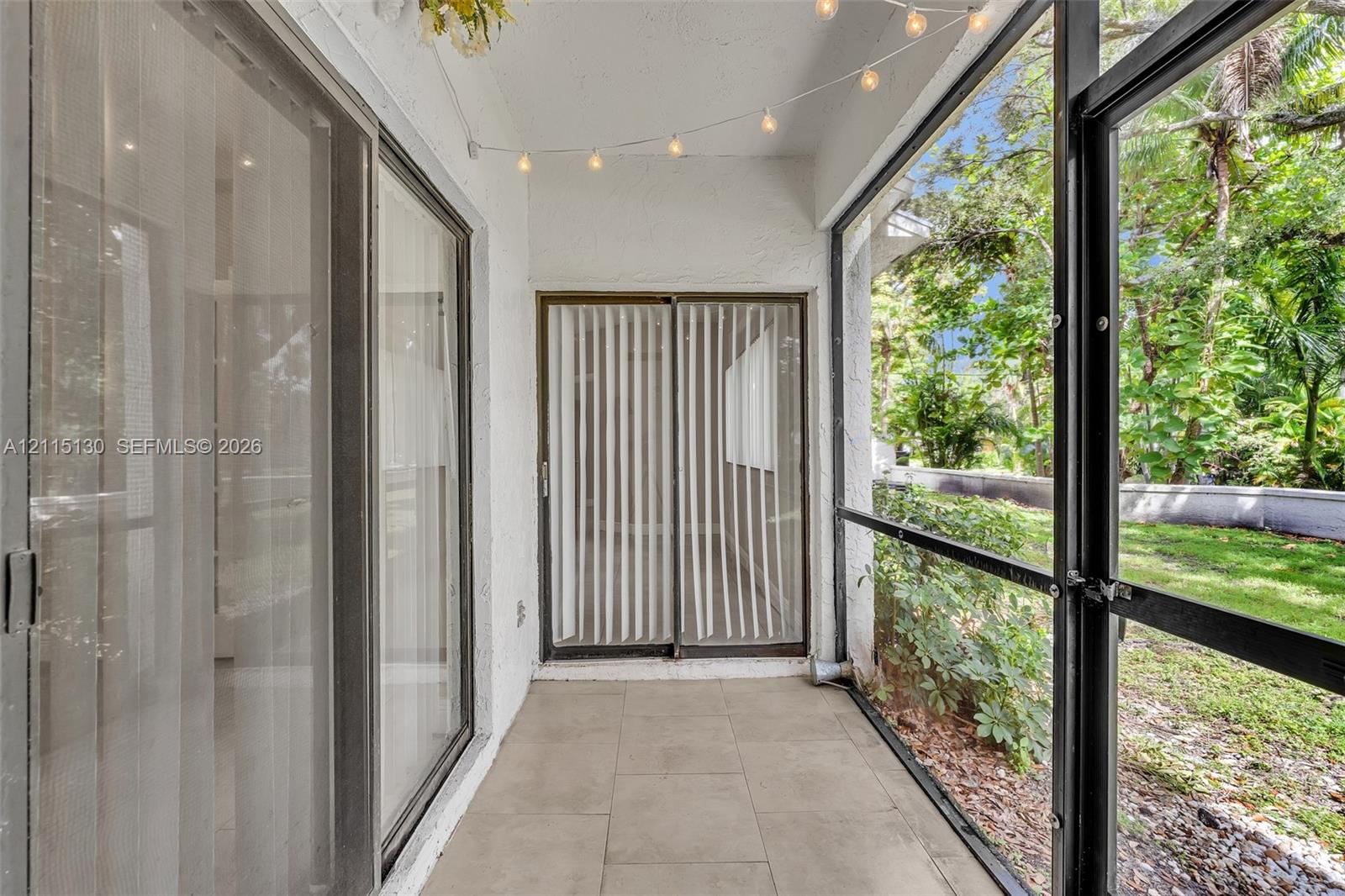 Screened-in patio featuring tile flooring, sliding glass door access, and exterior metal framing