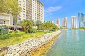 Waterfront high-rise building featuring a stone-reinforced bulkhead, expansive landscaped grounds, and mature palm trees Waterfront high-rise building featuring a stone-reinforced bulkhead, expansive landscaped grounds, and mature palm trees